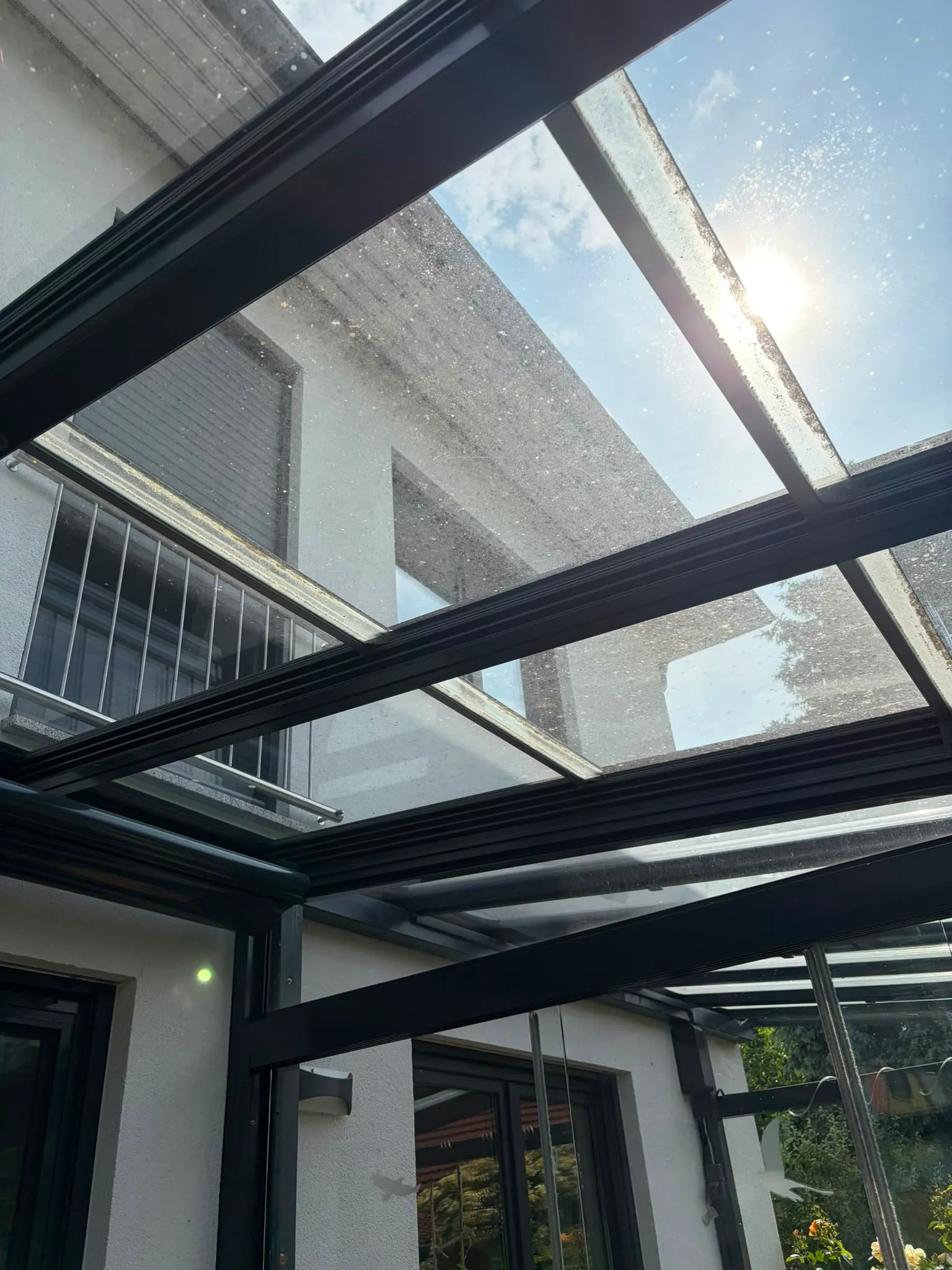 Anthrazitfarbenes Terrassendach mit Wasserflecken und Ablagerungen vor der Reinigung