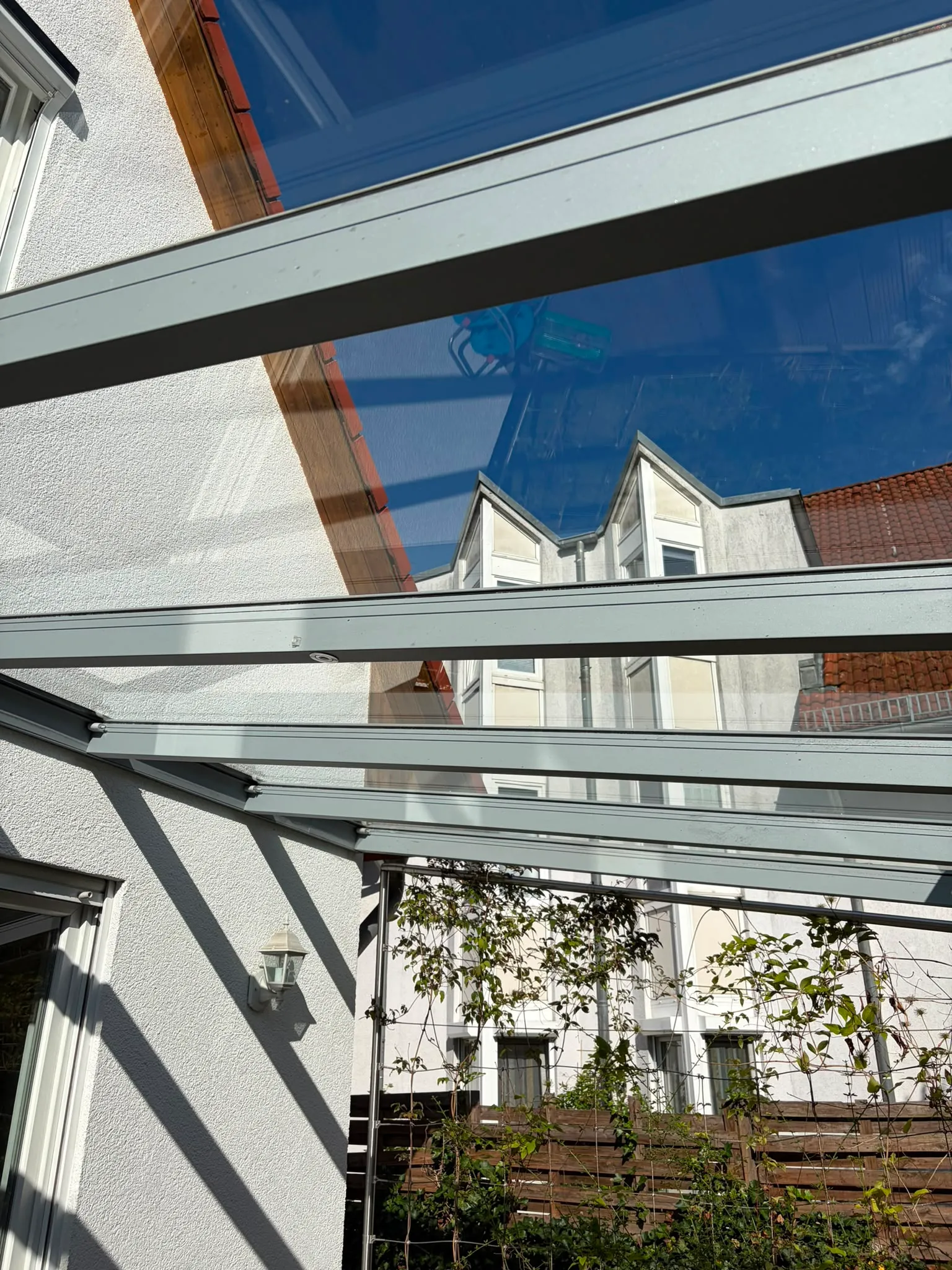 Klar gereinigtes Glasdach einer Terrassenüberdachung mit blauem Himmel